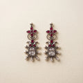 Ornate silver earrings with red gemstones on a beige background